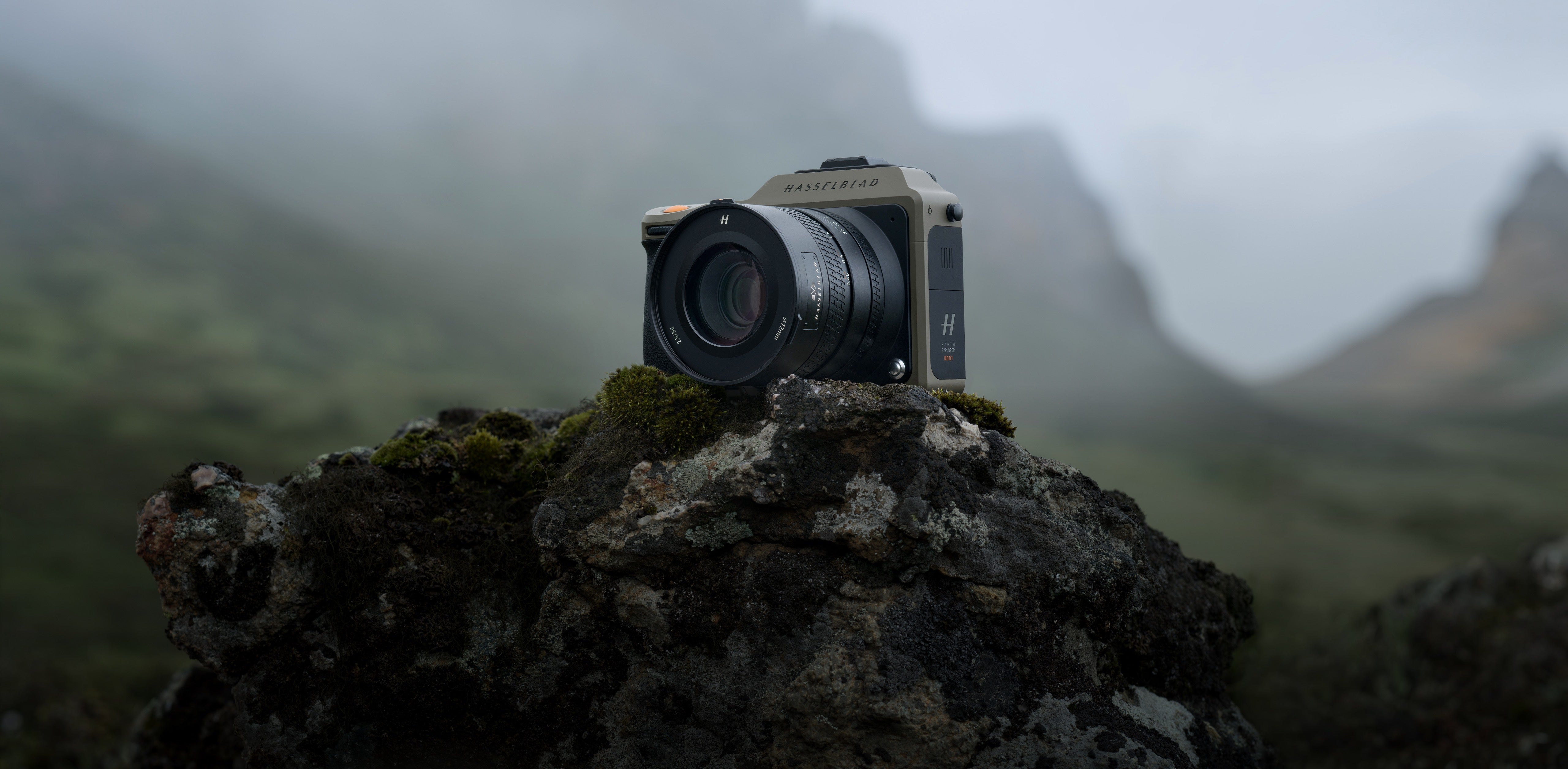 哈蘇相機置於長滿青苔的岩石上,背景是雲霧繚繞的山谷